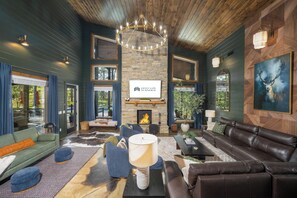 A spacious living room with a fireplace, leather sofas, and a chandelier.