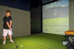 A person practicing golf indoors with a screen displaying a golf course. - Luxury Resort | Golf Sim, Pool, Gym, Sauna, 30 ppl (Broken Bow)