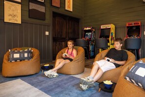 A room with bean bag chairs, arcade games, and a popcorn bowl. - Luxury Resort | Golf Sim, Pool, Gym, Sauna, 30 ppl (Broken Bow)