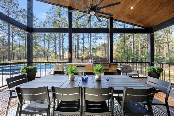 A covered outdoor patio with a pool, seating, and an outdoor kitchen.