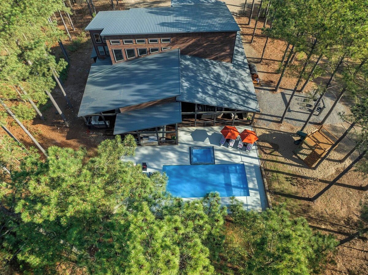 Un bâtiment à deux étages doté d’une piscine et d’un espace extérieur aménagé pour s’asseoir.