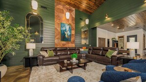 A modern living room with a sectional sofa, a coffee table, and a large mirror. - Luxury Resort | Golf Sim, Pool, Gym, Sauna, 30 ppl (Broken Bow)