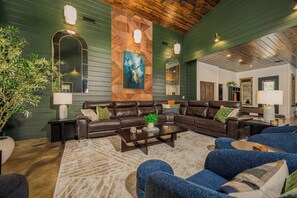 A modern living room with a sectional sofa, a coffee table, and a large mirror. - Luxury Resort | Golf Sim, Pool, Gym, Sauna, 30 ppl (Broken Bow)