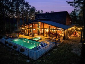 A modern house with a swimming pool, outdoor seating, and a hot tub.