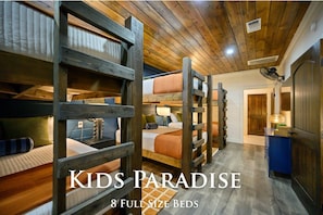 A children's hostel with 8 full-size beds arranged in a row, wooden bunk beds, and a fan on the ceiling. - Luxury Resort | Golf Sim, Pool, Gym, Sauna, 30 ppl (Broken Bow)
