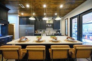 A modern kitchen with a central island, stainless steel appliances, and pendant lighting. - Luxury Resort | Golf Sim, Pool, Gym, Sauna, 30 ppl (Broken Bow)