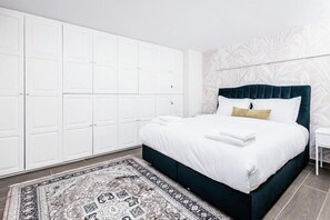 A bedroom with a bed, a white wardrobe, a patterned rug, and a wall with a leaf pattern. - MZ Kolonaki Hills (Athens)