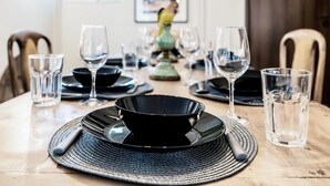 A dining table set with black plates, clear glasses, and a woven placemat. - MZ Kolonaki Hills (Athens)