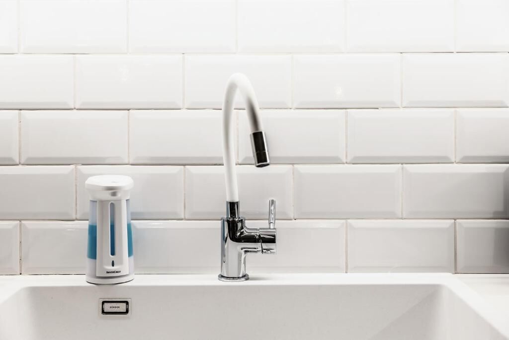 A modern kitchen sink with a chrome faucet, a soap dispenser, and a soap dish.