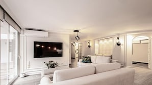 A modern living room with a flat-screen TV, a sofa, and a decorative light fixture. - MZ Kolonaki Hills (Athens)