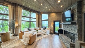 A spacious living room with a fireplace, large windows, and a ceiling fan. - Best Views • Indoor Pool • Hot Tub • Romance (Sevierville)