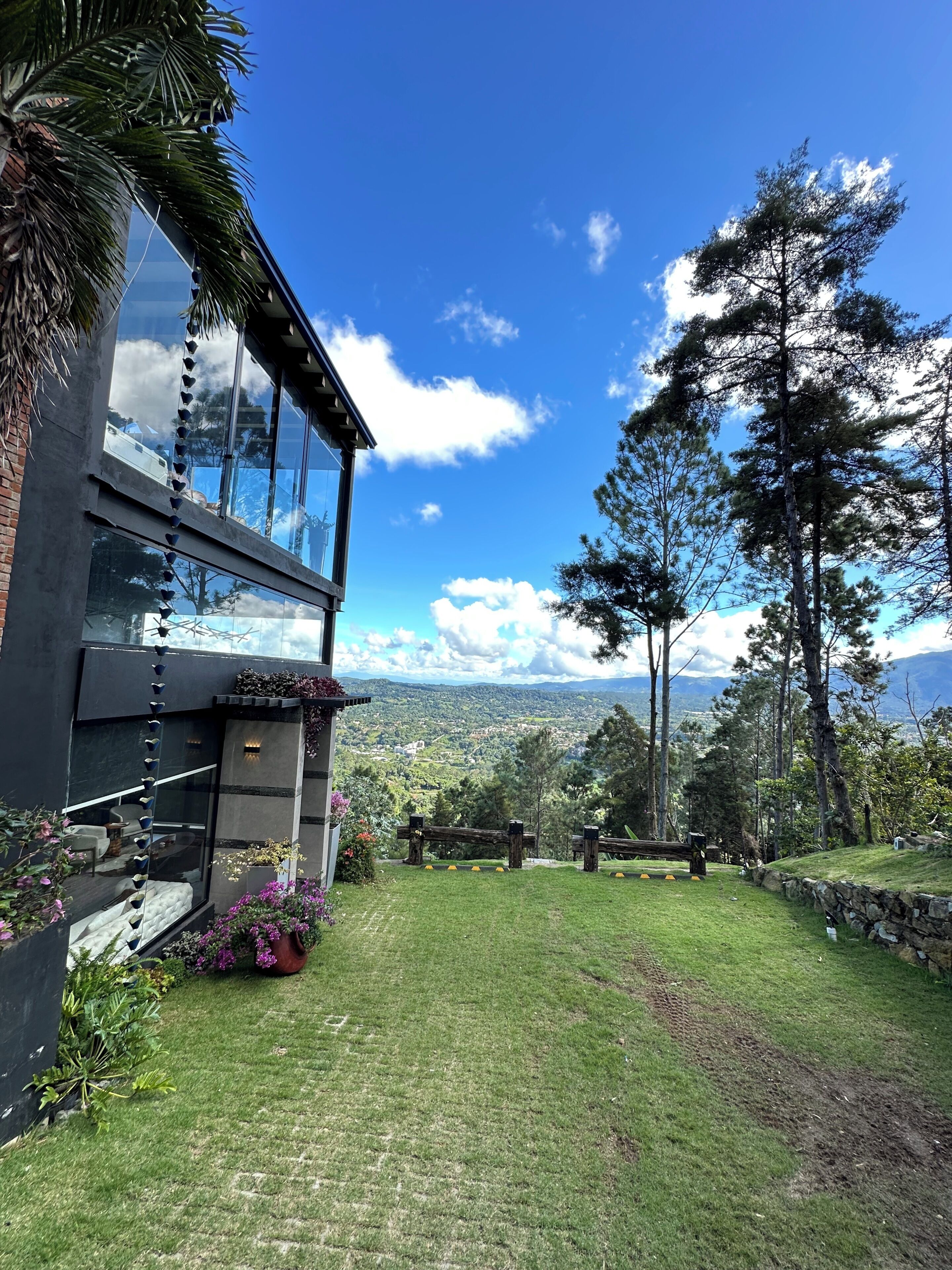 A modern building with large windows, a grassy yard, and a view of a mountainous landscape.