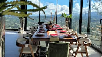 A modern dining area with a long table, chairs, and a view of the landscape.