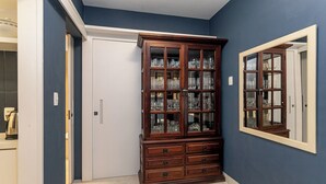 A room with a dark blue wall, a wooden cabinet with glass doors, a white door, and a mirror on the wall. - Leme 300 m praia 2 quartos conforto (Rio de Janeiro)