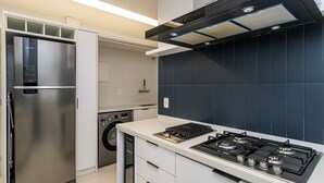 A compact kitchen with a stainless steel refrigerator, a dishwasher, and a gas stove. - Leme 300 m praia 2 quartos conforto (Rio de Janeiro)