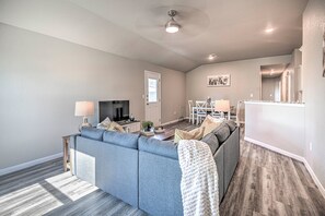 Ein Wohnzimmer mit Ecksofa, Fernseher und Essbereich mit Tisch und Stühlen.