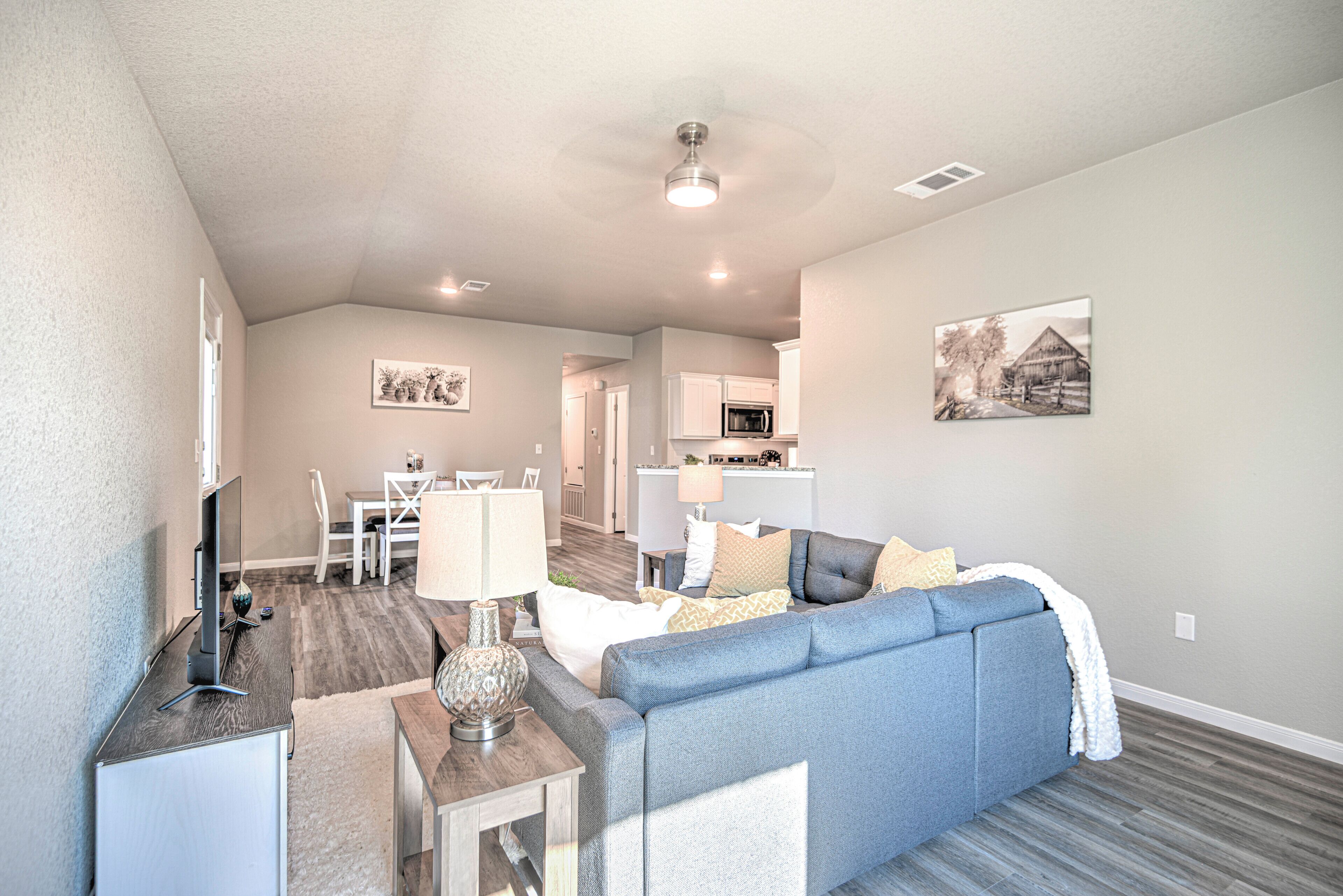 A modern living room with a sofa, a dining area, and a kitchen in the background.