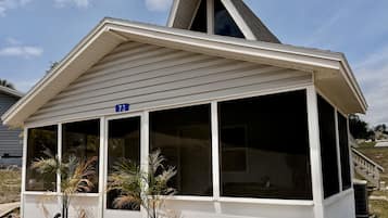 A house with a covered porch, a number sign '73', and two potted plants.