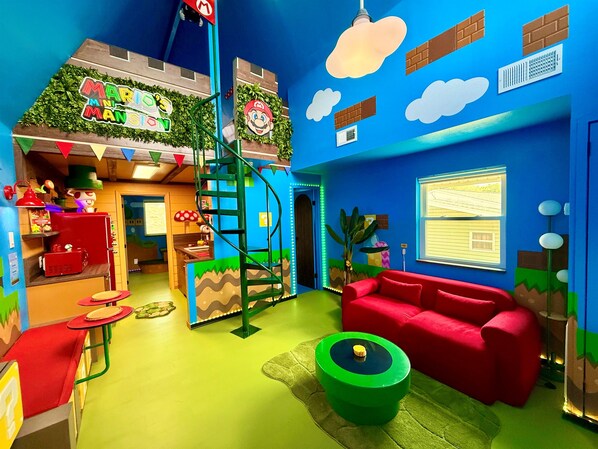 Een levendige kinderspeelruimte met een glijbaan, een rode bank en een groene tafel.