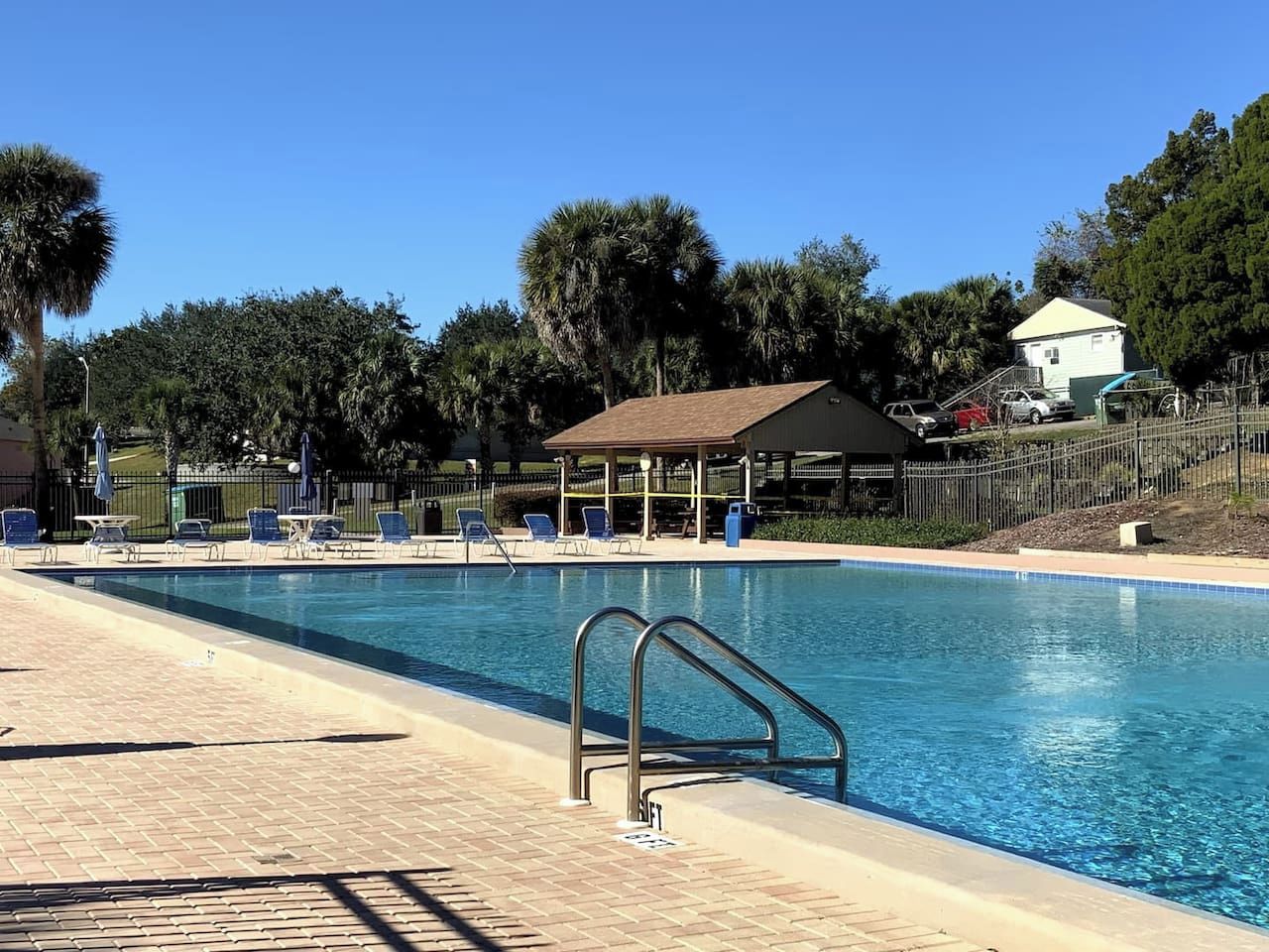 A swimming pool with a lifeguard stand, lounge chairs, and a covered pavilion.