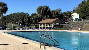 A swimming pool with a lifeguard stand, lounge chairs, and a covered pavilion.