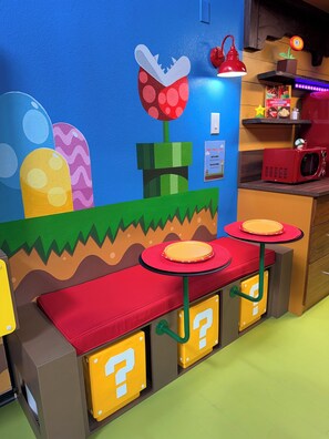 A children's play area with colorful seating, a red lamp, and a microwave on a shelf. - Mario's Mini Mansion: Themed Family Fun in Clermont, Florida! Locals Welcome (Clermont)
