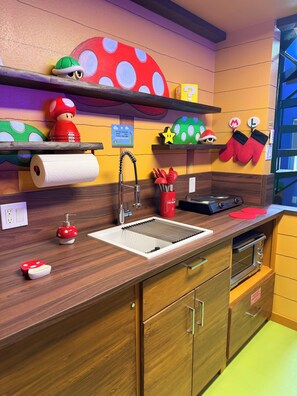 Une cuisine dotée d’un plan de travail en bois, d’un évier, d’un four encastré et de décorations sur le thème des champignons.