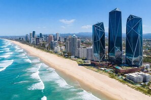 Eine Küstenstadt mit modernen Hochhäusern, einem Sandstrand und wolkenlosem, blauem Himmel.