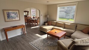 A living room with a sofa, coffee table, and a dining area with chairs and a table. - Spacious downtown oasis, free parking & laundry (Bellingham)