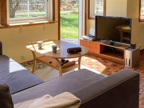 Una sala de estar con un sofá, una mesita de centro, un televisor y un mueble bajo.
