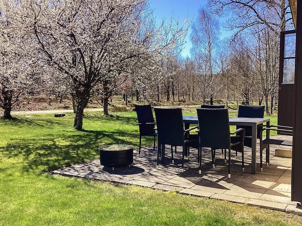 A patio with a table and chairs, surrounded by trees and a grassy area. - 6 Person Holiday Home in Ljungbyhed (Ljungbyhed)