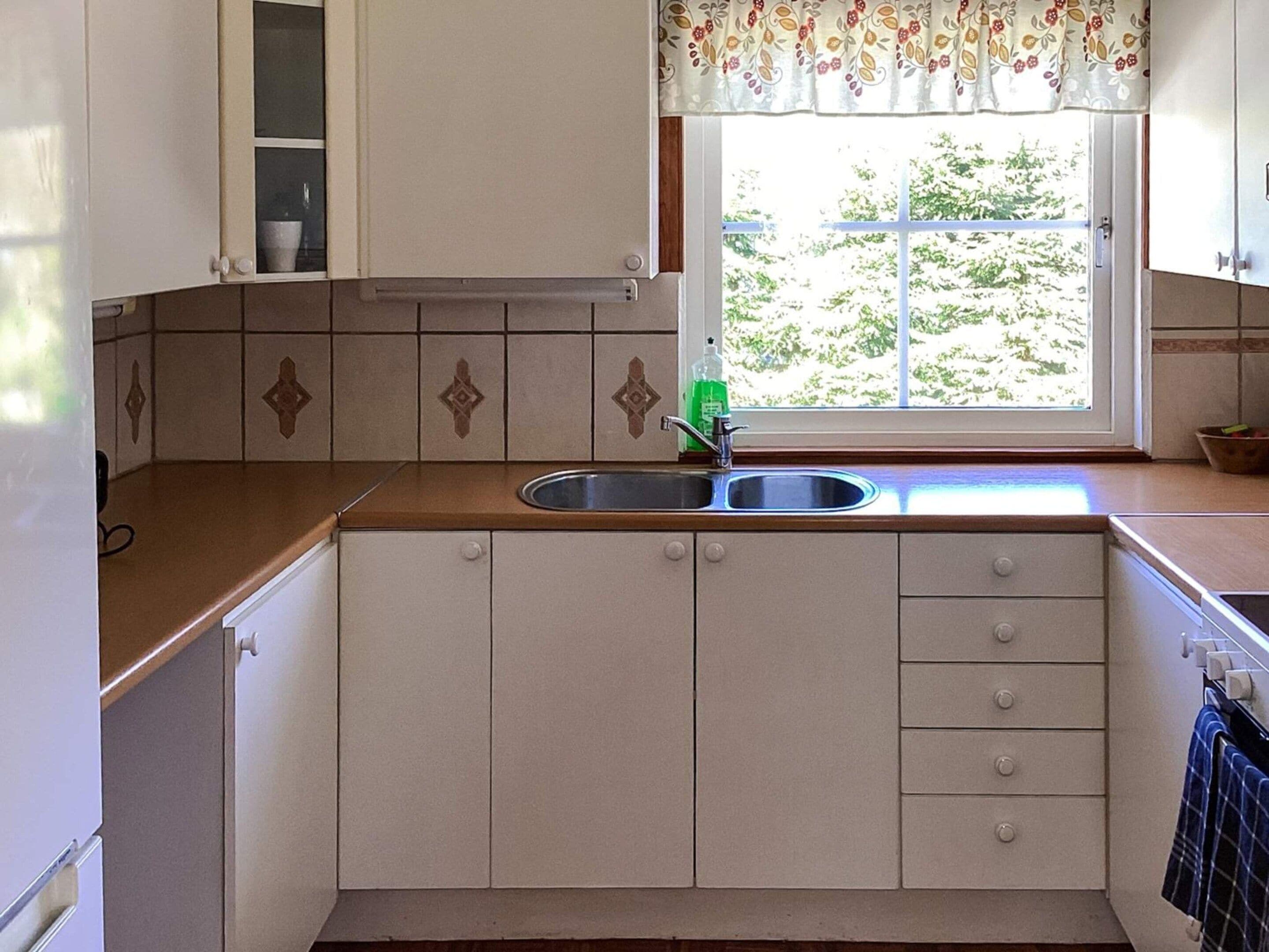 A kitchen with a window, a sink, and cabinets.