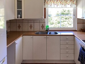 Una cocina con ventana, lavamanos y armarios.