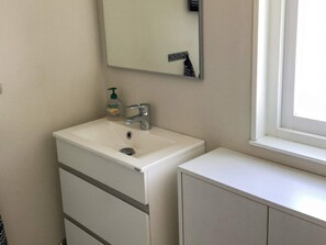 A bathroom with a white sink, a mirror, a window, and a cabinet. - 6 Person Holiday Home in Ljungbyhed (Ljungbyhed)