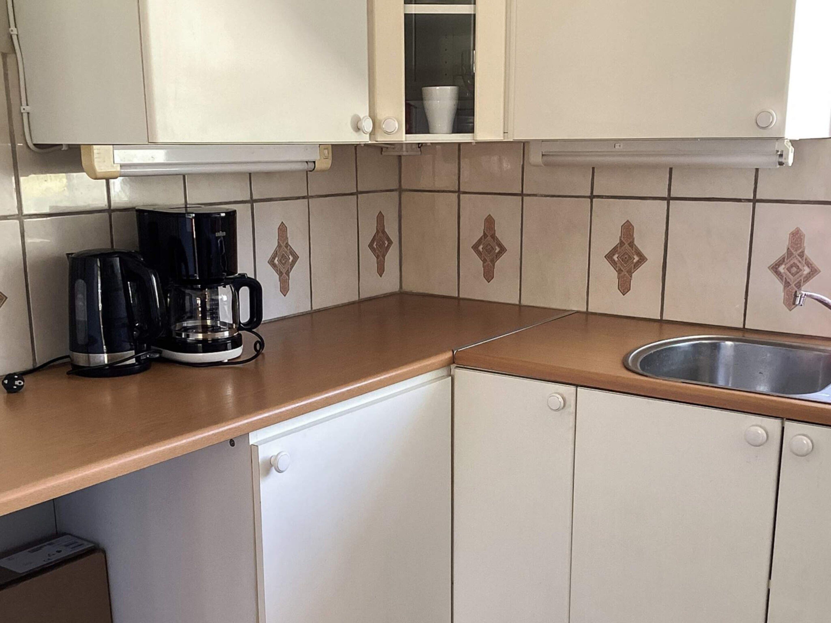 Eine Küche mit einer Kaffeemaschine, einem Spülbecken und Schränken.