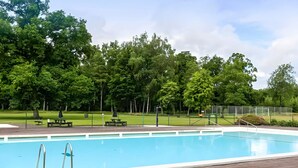 A swimming pool with a brick deck, surrounded by trees and a grassy area. - 6 Person Holiday Home in Ljungbyhed (Ljungbyhed)