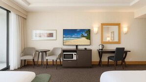 A hotel room with a bed, two armchairs, a desk with a computer, a television, and a large window with curtains. - Stunning Ocean View Studio Pool, Spa & Wi-Fi (Surfers Paradise)