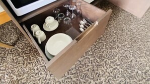 A drawer under a microwave containing a tea set, wine glasses, and cutlery. - Stunning Ocean View Studio Pool, Spa & Wi-Fi (Surfers Paradise)