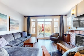 A living room with a sofa, armchair, coffee table, fireplace, and large windows. - Eagle`s Escape at Blue Mtn: Summer Pool + Hot Tub (The Blue Mountains)
