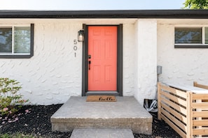 A house with a red door, a mailbox, and a wooden gate.