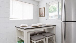 A compact kitchen with a white countertop, two bar stools, a stainless steel refrigerator, and a window with blinds. - NEW Owner Special King Bed Colorful Quay Themed Duplex Workspace Fuquay-Varina (Fuquay-Varina)