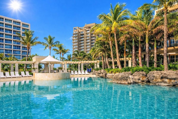 A pool area with lounge chairs, a gazebo, palm trees, and high-rise buildings in the background. - L17 Small Studio Suite 2 Beds Pool Spa (Surfers Paradise)