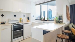 Una cocina moderna con un amplio ventanal, horno empotrado y una isla central con taburetes.