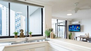 Una cocina moderna con un amplio ventanal, un televisor de pantalla plana y un comedor con mesa y sillas.