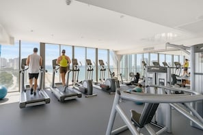 A gym with treadmills, ellipticals, and exercise balls, large windows with a city view. - Level 11 Ocean view Escape (Surfers Paradise)