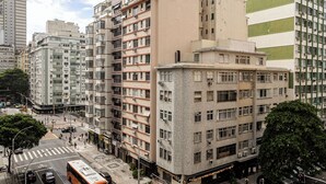 A multi-story building with a mix of residential and commercial spaces, including a visible crosswalk and parked vehicles. - Copacabana 2 quartos e vista mar (Rio de Janeiro)