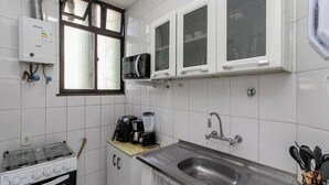 A kitchen with a gas stove, microwave, and a built-in oven. - Copacabana 2 quartos e vista mar (Rio de Janeiro)