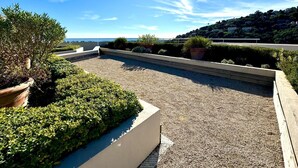 A rooftop terrace with a gravel surface, potted plants, and a view of the sea. - Elegant new T2 with sea view, pool and gym in a refined setting. (Mandelieu-la-Napoule)