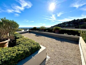 A rooftop terrace with a gravel surface, potted plants, and a view of the sea. - Elegant new T2 with sea view, pool and gym in a refined setting. (Mandelieu-la-Napoule)