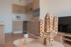 A modern kitchen with wooden cabinets, a built-in oven, and a television. - Elegant new T2 with sea view, pool and gym in a refined setting. (Mandelieu-la-Napoule)